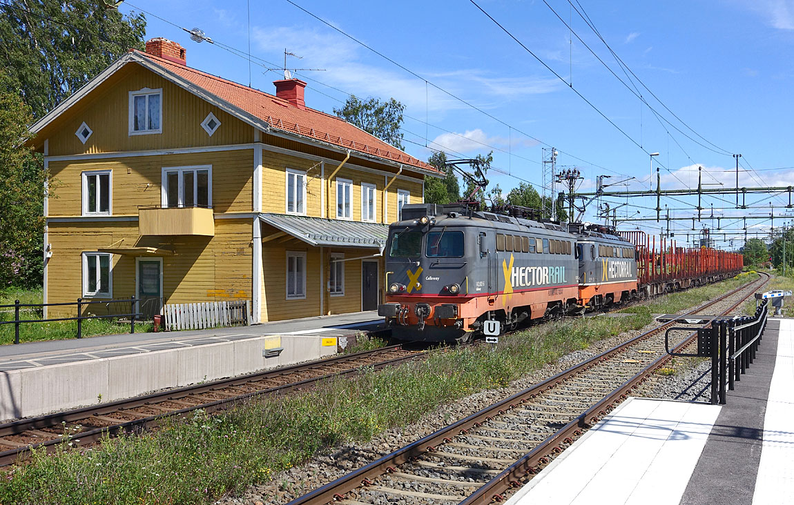 Ett tomtåg draget av två 142-lok på väg till virkesterminalen i Storflon passerar Gällö i juli 2015. Foto Markus Tellerup.