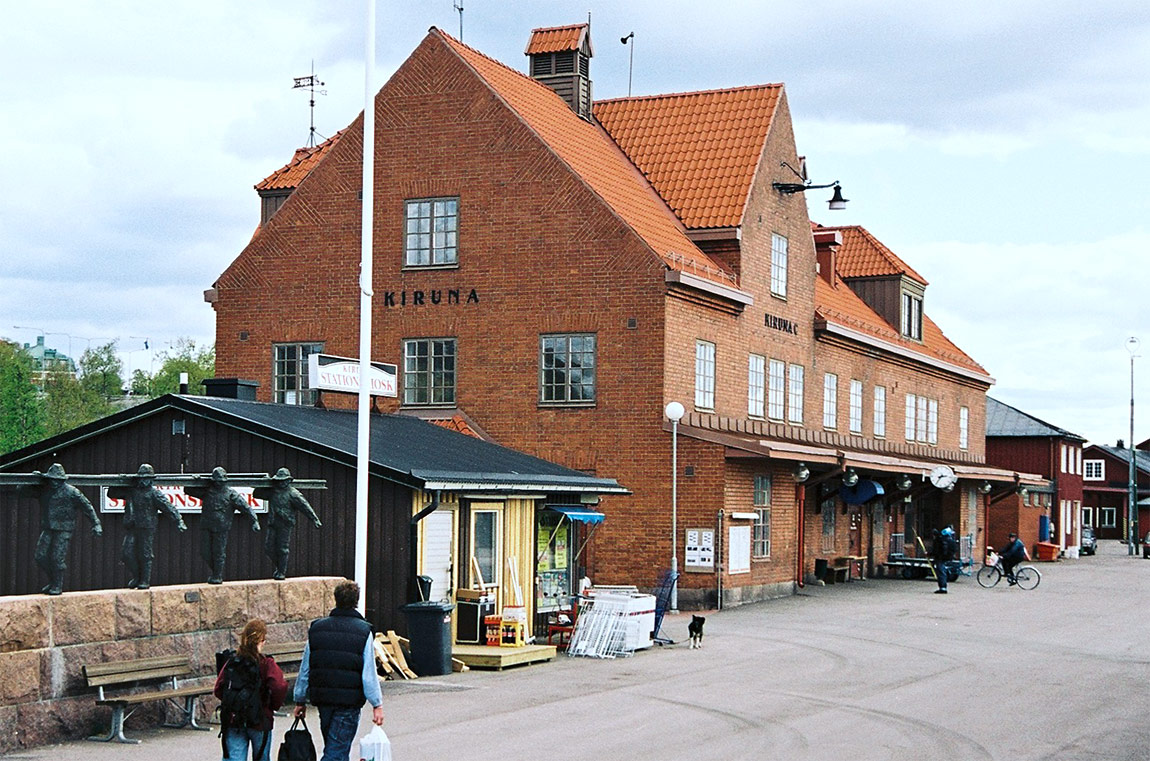 Kirunas dåvarande stationshus, byggt 1915 och ritat av Folke Zettervall, sommaren 2003. Rallarmonumentet (till vänster i bild) har fått flytta med till den nuvarande provisoriska stationen i Kiruna. Foto Markus Tellerup.