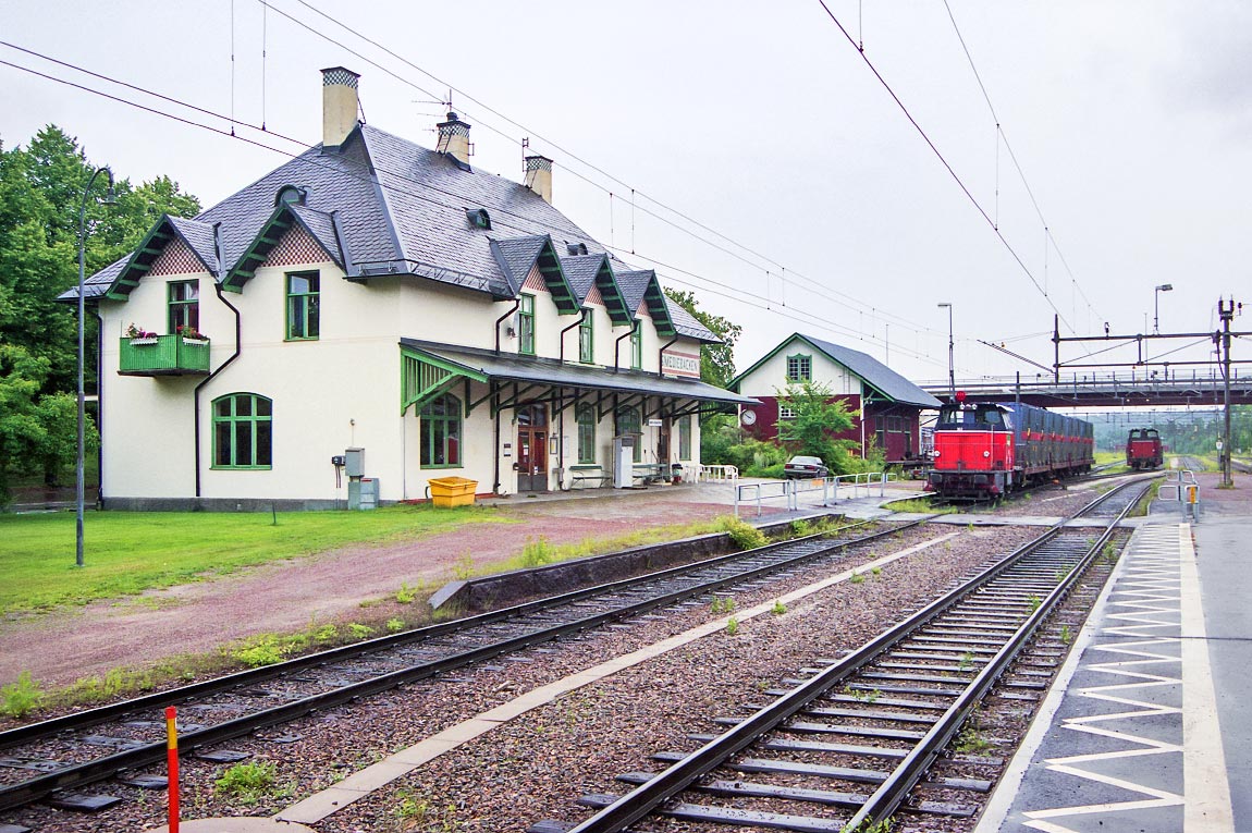 Stationen i Smedjebacken i juli 2003. På bangården växlar diesellok typ V5. Stationshuset är ett exempel på de stationshus i jugendstil som Erik Lallerstedt ritade åt  SWB när de byggde järnvägen från Ängelsberg upp till Vansbro. Foto Markus Tellerup.