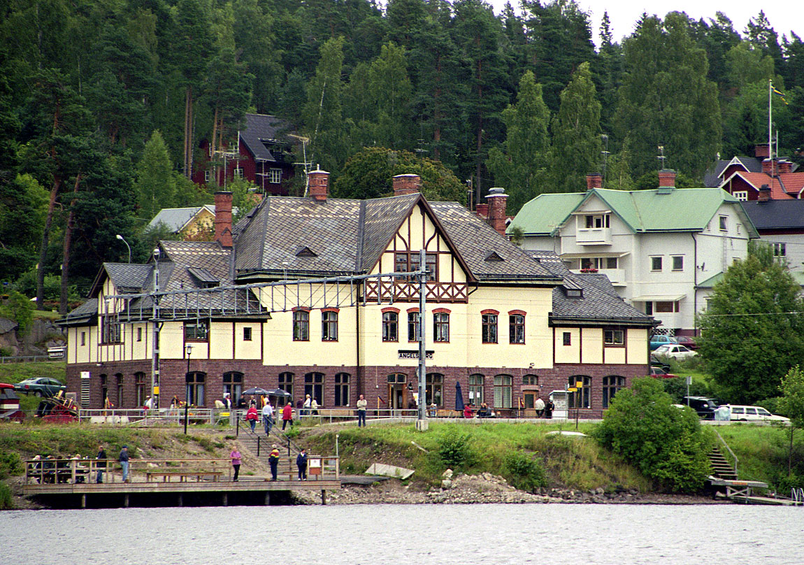 Ängelsbergs station sedd från sjösidan. Nedanför stationshuset ligger bryggan för färjan över till Oljeön. Foto 2003, Markus Tellerup.