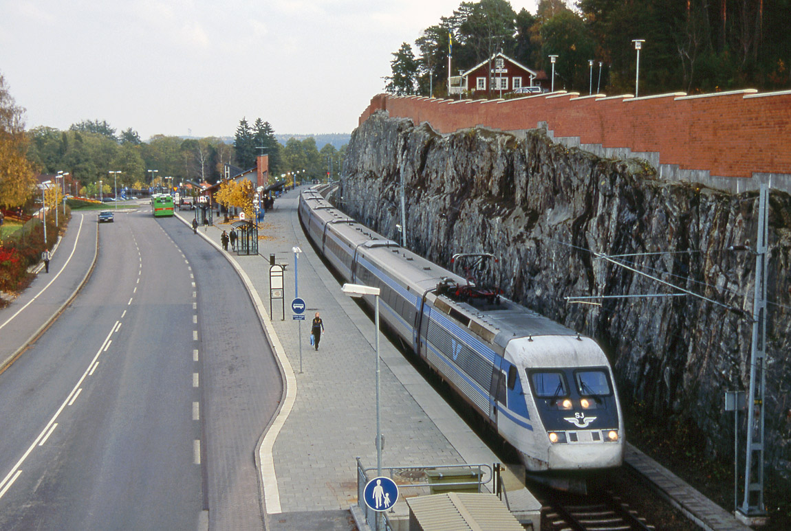 Ett X2-tåg mot Eskilstuna lämnar stationen i Strängnäs den 8 oktober 2000. Ett gott stycke av Långberget sprängdes bort för att få utrymme till den nya stationen, men till mötesspår fanns det inte plats eller pengar - då. Hösten 2014 startade arbetet med en andra tunnel under Långberget och en ny tvåspårig station. Foto Markus Tellerup.