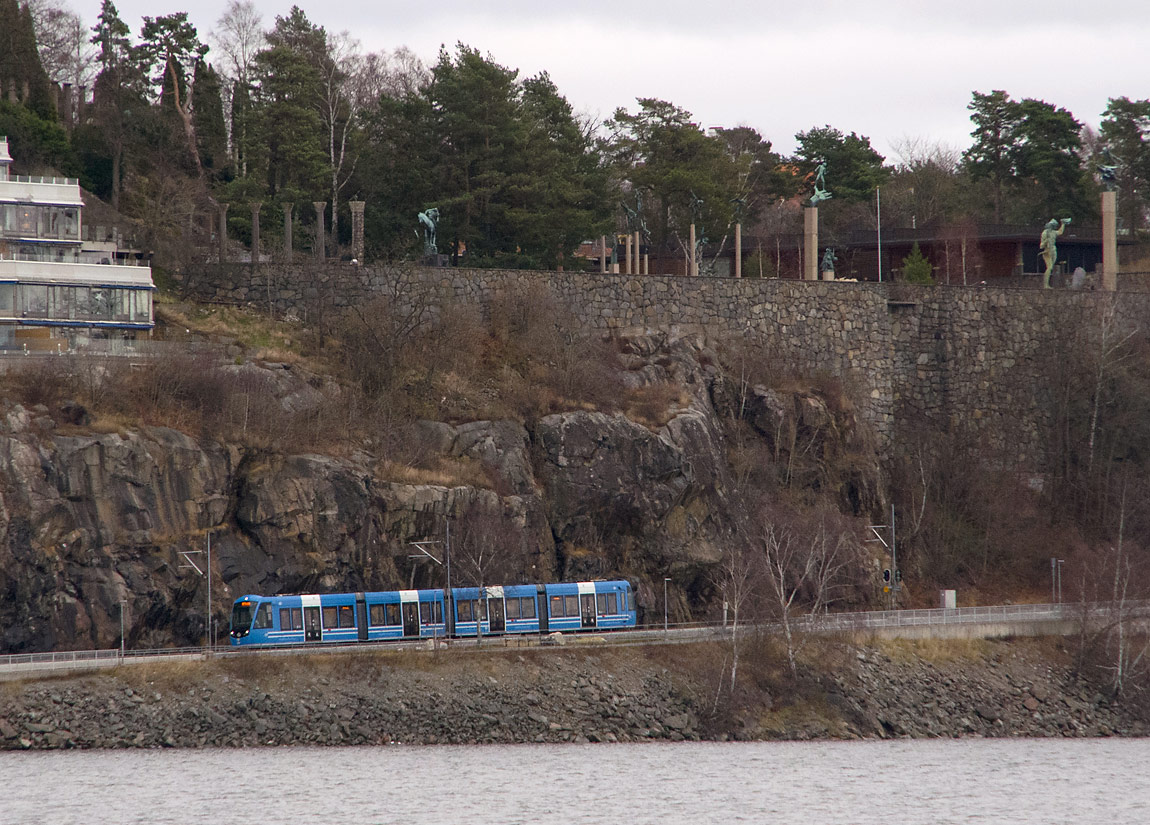 Bild: Ett tåg närmar sig Torsvik på väg mot Ropsten i december 2015. Ovanför banan ligger Millesgården med bland annat den berömda "Guds hand" av skulptören Carl Milles. Foto Markus Tellerup.