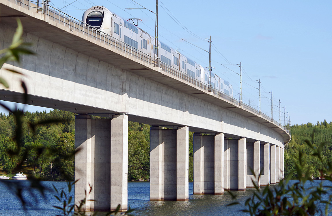 Bild: Ett femvagnars X40-tåg från Stockholm på väg mot Västerås och Göteborg passerar Ekolsundsbron i hög fart den 26 augusti 2017. Foto Markus Tellerup.