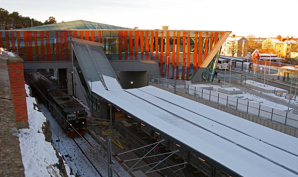 I december 2017 hade det nya stationshuset och resecentrat i Strängnäs öppnat. Ett tåg mot Stockholm anländer. Den nya tunneln och det nya spåret (dolt bakom plattformstaket) var dock ännu inte i bruk. Foto Markus Tellerup.