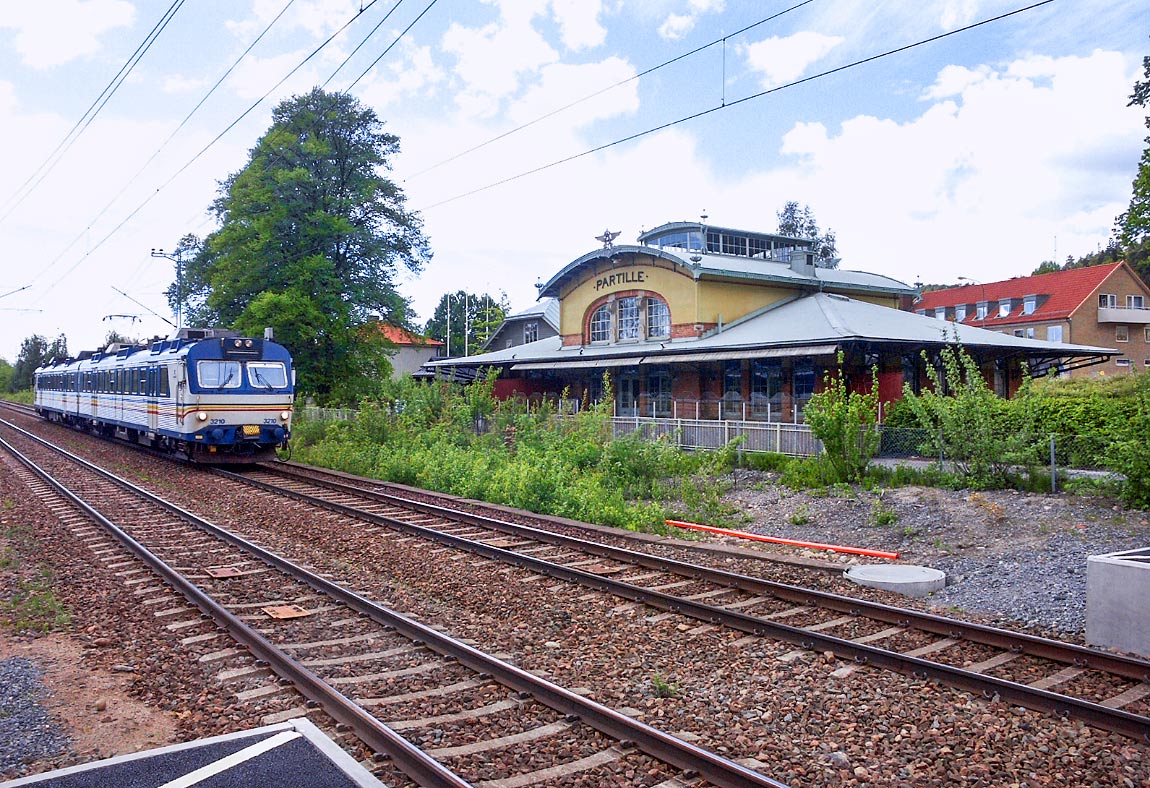 Ett pendeltåg på väg mot Alingsås i Partille i mitten av maj 2004. I det före detta stationshuset finns en restaurang. Foto Markus Tellerup.