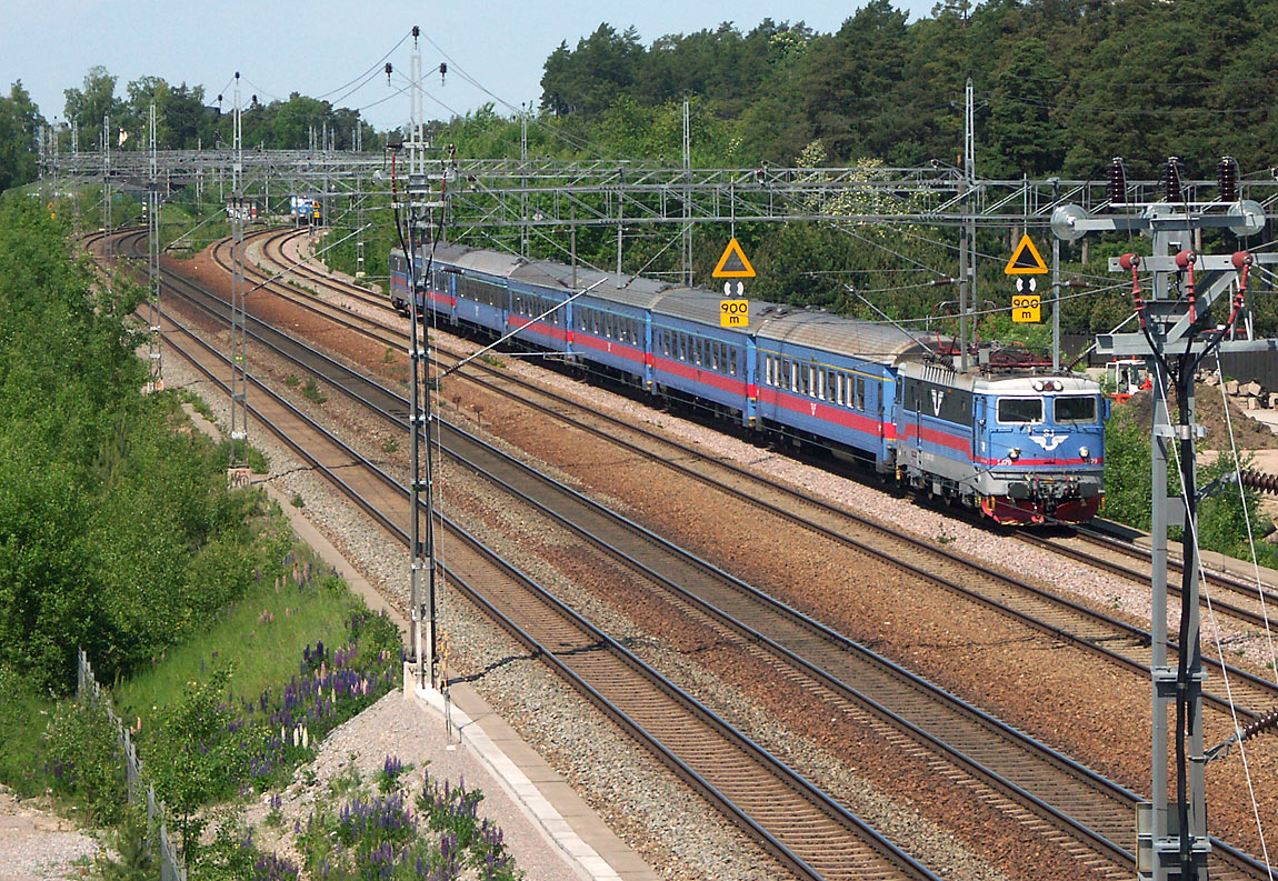 Tåg Uppsala-Eskilstuna strax söder om Helenelund i juni 2004. I bakgrunden ett pendeltåg som just startat efter uppehållet i Helenelund. Foto Markus Tellerup.