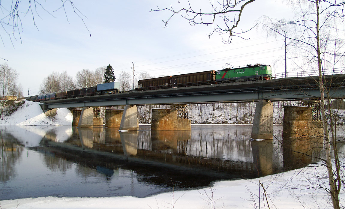 Ett södergående godståg på bron över Dalälven vid Krylbo vintern 2007. I bakgrunden syns pelarna till den äldre järnvägsbron som numera endast används för biltrafik. Foto Markus Tellerup.