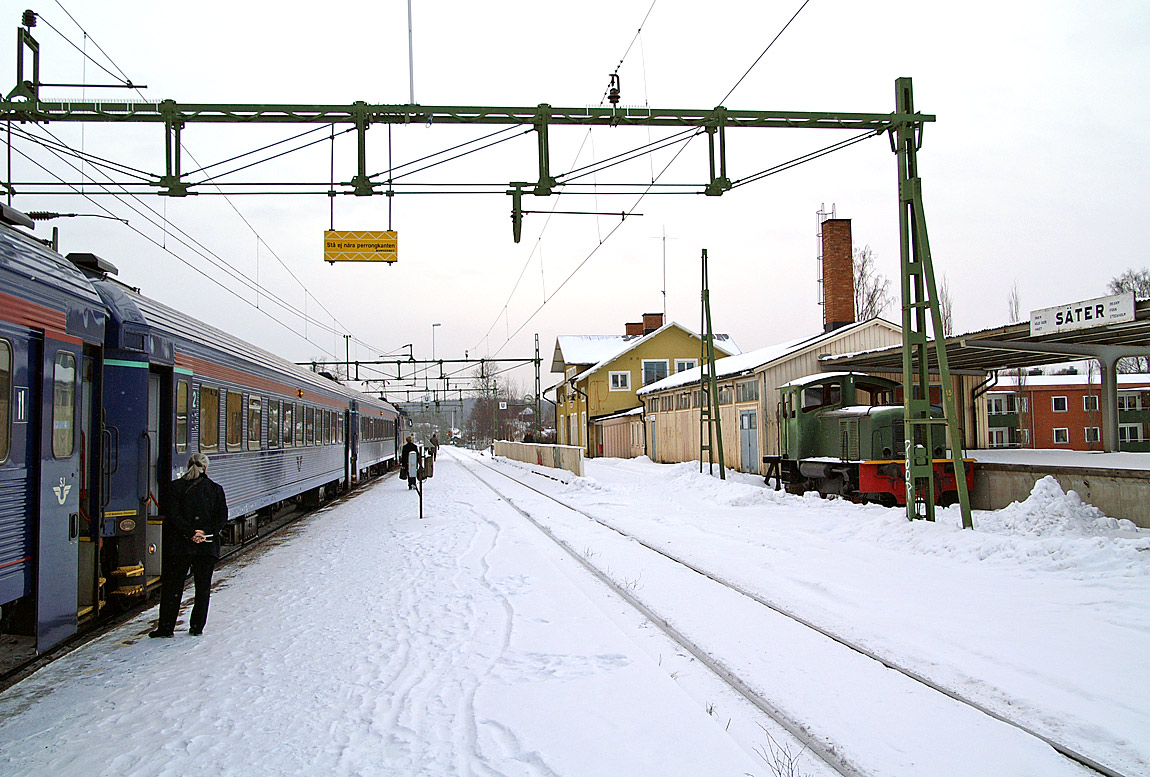 Den ruffiga stationsmiljön i Säter vintern 2007. Tåg mot Falun gör uppehåll. Den avställda lokomotorn till höger tillverkades av ASJ i Falun 1957 för Kvarnsvedens pappersbruk. Foto Markus Tellerup.