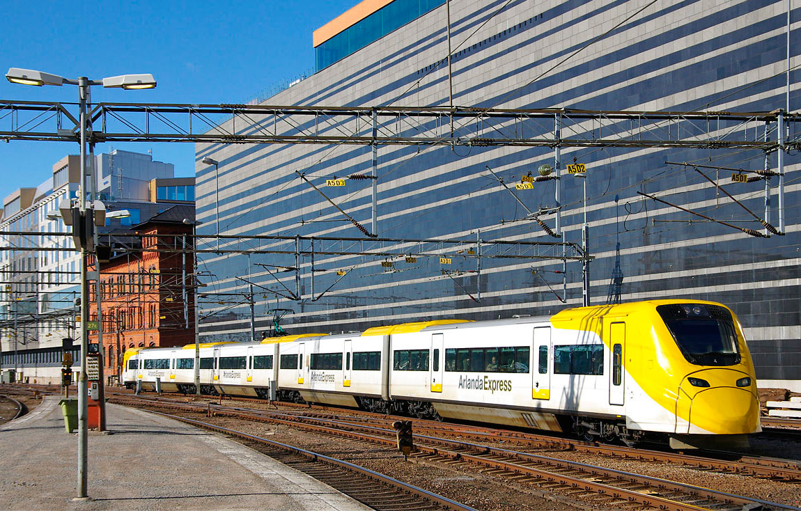 Arlanda Express ankommer Stockholm Central den 25 mars 2011. Bortom hotell Clarion Signs massiva fasad står SJ:s gamla expeditionshus från 1894 kvar som en påminnelse om järnvägens långa historiska arv. Foto Markus Tellerup.