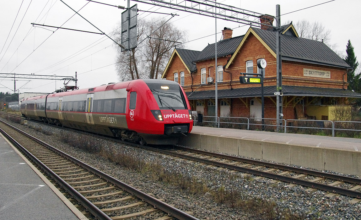 Upptåget stannar till i Skyttorp i november 2014. På det före detta stationshuset anges inte avståndet till Stockholm, däremot till Gävle och Uppsala - ett arv från tiden som enskild järnväg. Foto Markus Tellerup.