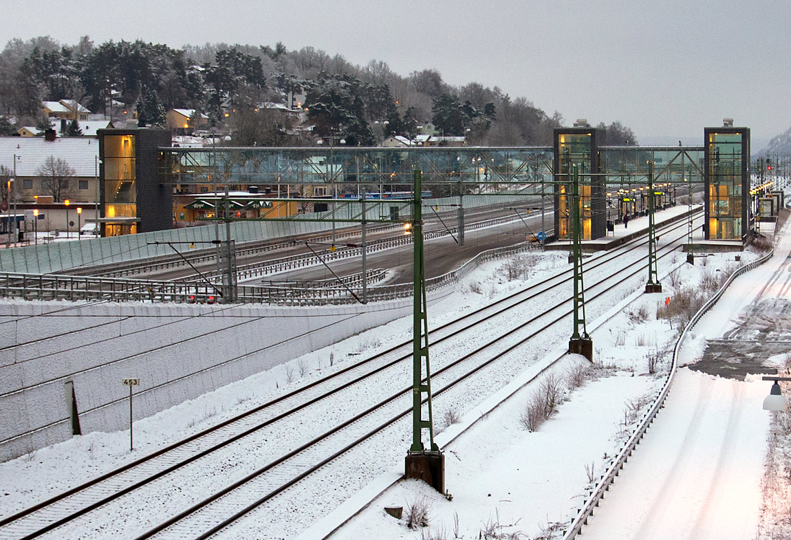 Stationen i Nol 2014. De sex nya pendeltågsstationerna mellan Göteborg och Älvängen utmärker sig med sina hisstorn och långa inglasade gångbroar som i flera fall även sträcker sig över den nya motorvägen som byggts jämsides med den dubbelspåriga järnvägen. Foto Markus Tellerup.