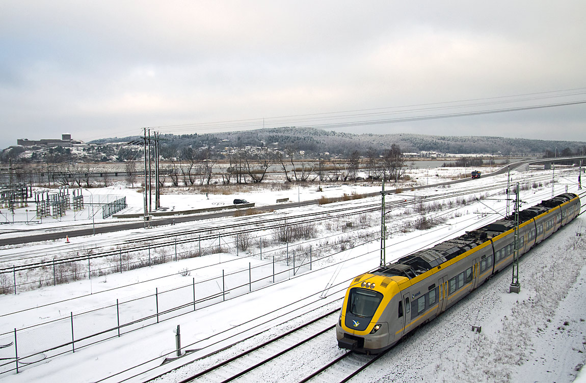 Ett pendeltåg Älvängen-Göteborg bestående av en X61-motorvagn i Bohus i december 2014. På andra sidan Göta älv syns Bohus fästning. Foto Markus Tellerup.