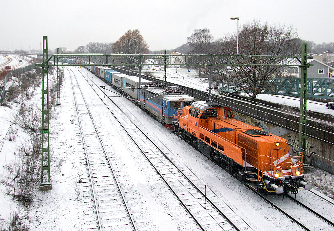 Ett Voith Gravita-lok drar ett av Hector Rails långa containertåg förbi Pölsebo den 28 december 2014. Det overksamma elloket är av typen 143 (fd Rc3). Foto Markus Tellerup.
