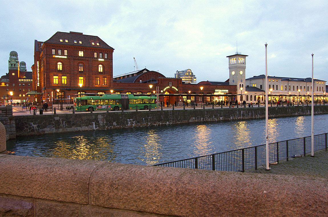 Malmö C domineras av Folke Zettervalls tegelbyggnader från 1890-talet. Klocktornet är det enda som återstår av det ursprungliga stationshuset från 1856 som brann ned tio år senare och ersattes av huset till höger. Bakom dessa byggnader finns idag även den glastäckta vänthallen ovanför Malmö C Nedre. Längst till vänster syns Centralposthuset. Foto 2015, Markus Tellerup.