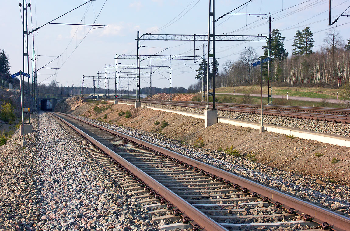 Vid Skavstaby viker den egentliga "Arlandabanan" av mot nordost från den gamla linjen. Uppspåret (för tåg mot Arlanda) korsar de två spåren mot Märsta i tunnel. Foto i april 2005, Christian Tellerup.