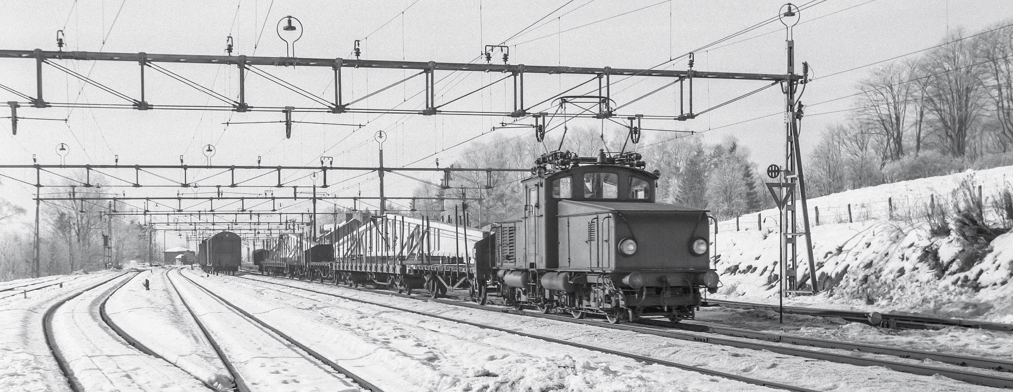 Hb-lok med godståg lastat med betongbalkar från Strängbetong i Kinna 1963